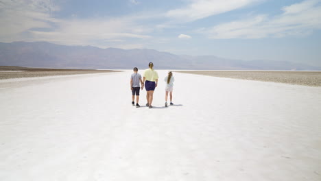 family walking across a vast salt flat in a desert landscape