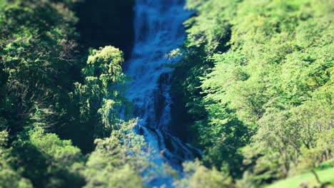 Una-Toma-Con-Efecto-De-Cambio-De-Inclinación-De-La-Cascada-En-Los-Acantilados-Verdes,-Empinados-Y-Cubiertos-De-Bosques-Del-Fiordo-De-Naeroy.