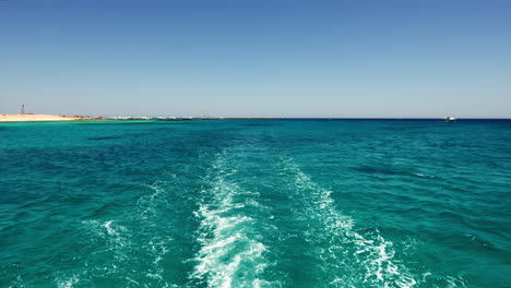 Seascape-Boot-Rückansicht,-Segeln-Auf-Türkisfarbenem-Meerwasser-An-Der-Küste-Im-Sommertag,-Orange-Bay-Region-Hurghada-Ägypten,-Blick-Auf-Die-Küste-Am-Wasser