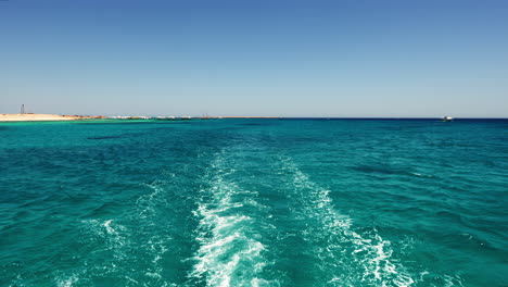 seascape boat rear view, sailing on turquoise sea water by coast in summer day, orange bay region hurghada egypt, waterfront coastal view