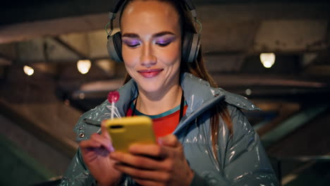 brunette listening music wireless headphones at night walk close up. happy woman