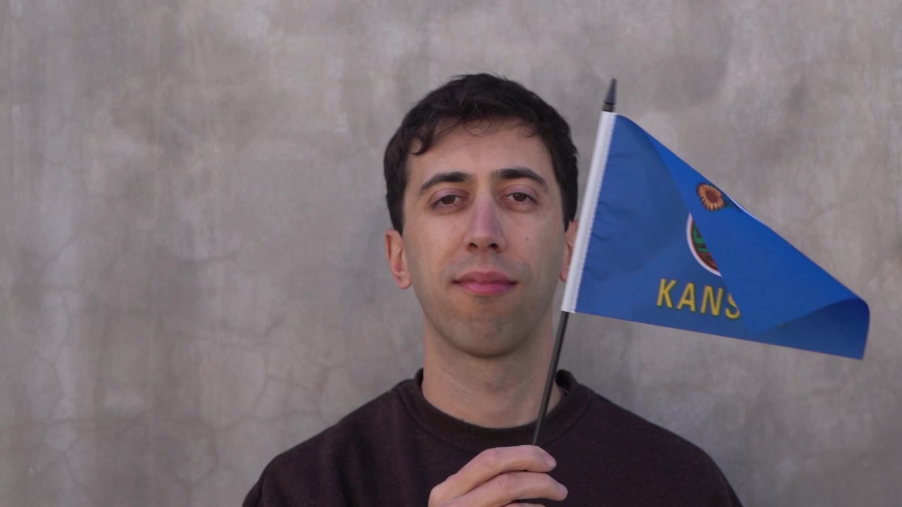 Osoba rasy kaukaskiej machająca flagą Kansas w zwolnionym tempie. Koncepcja flag stanów USA.