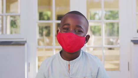 portrait of african american boy wearing face mask outdoors on a bright sunny day