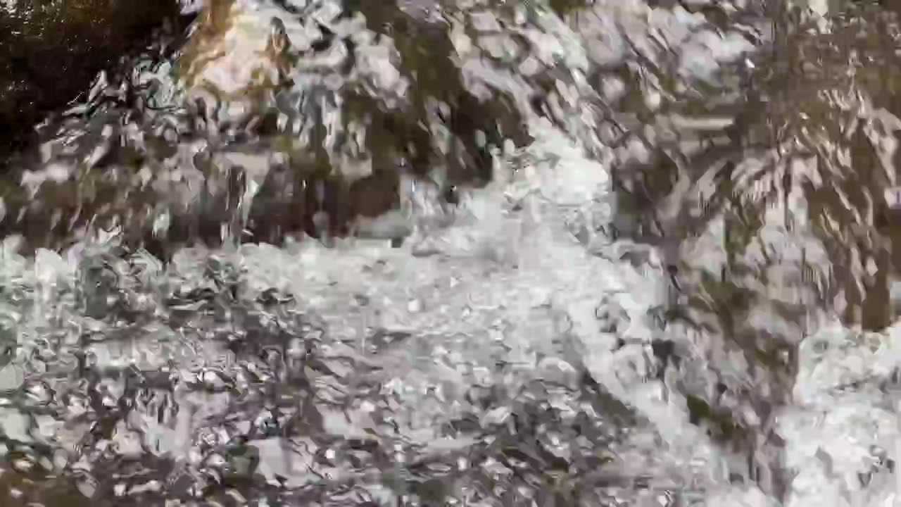 Primo piano di acqua limpida che scorre su rocce scure del fiume