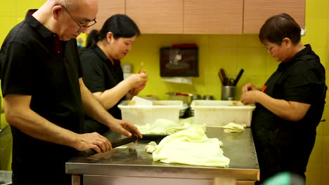 chefs preparing dough together in a kitchen