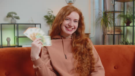 успешная богатая молодая белая женщина с банкнотой евро вентилятор денег сидит на диване диван дома