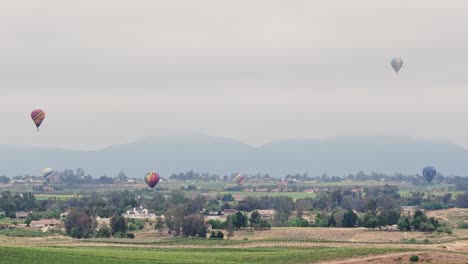 Temecula-Ballon--Und-Weinfest-Sechs-Heißluftballons-Sichtbar,-Als-Die-Drohne-Langsam-Nach-Hinten-Zieht