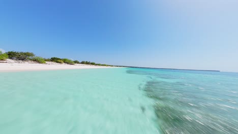 Drone-flight-over-empty-sandy-beach-with-turquoise-Caribbean-Sea-water-in-sunlight