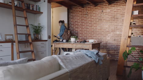 hermosa mujer joven preparándose para salir del apartamento con la bicicleta tarde para el trabajo