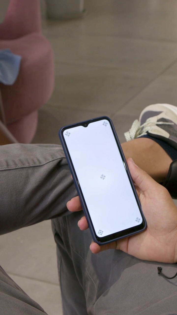 Video verticale: Uomo che aggiusta il telefono inclinando, muovendo la presa nella hall mentre appaiono dei mirini, con orologio.