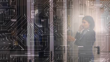 Woman-working-in-a-server-room-on-the-phone-with-glowing-circuit-board-in-foreground