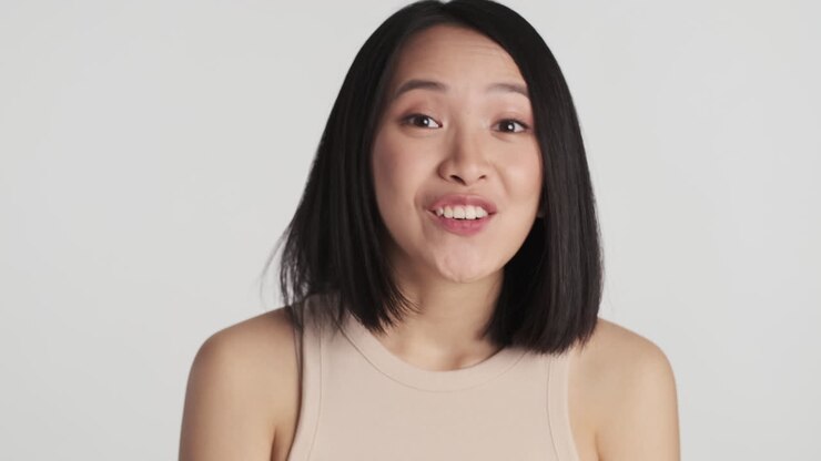 Asian woman looking surprised on camera.