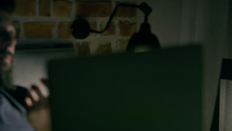 video de un hombre trabajando desde casa en su computadora portátil por la noche.