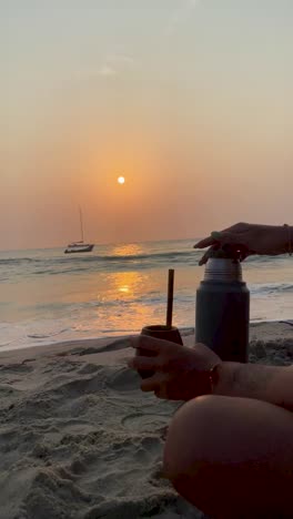 bebiendo mate mientras disfruta de una serena puesta de sol sobre el océano en cartagena