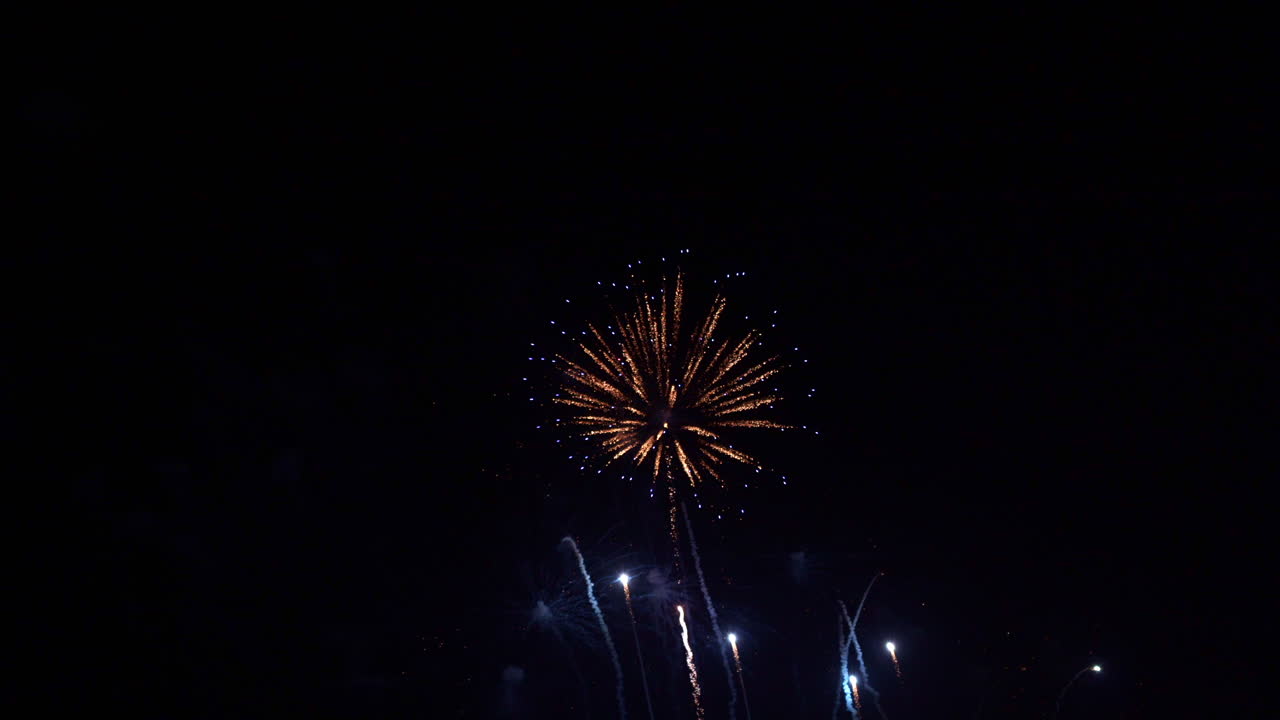 Colorful sparkling explosions of light shimmer in the black night sky. Stunning fireworks display for celebration of New Year or Independence Day. Pyrotechnic show with flashes and bursts of color