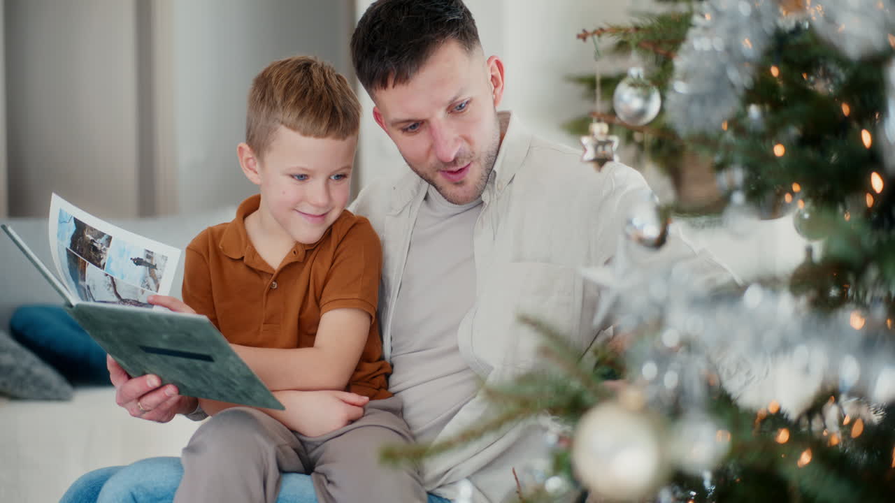 아빠와 아들은 크리스마스 트리를 장식하고 오래된 사진 앨범을 살펴봅니다.