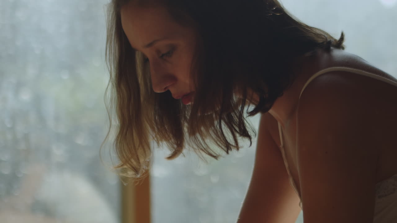 아침 햇살에 침대에 앉아 휴대폰으로 문자를 보내는 젊은 반쯤 벗은 여자