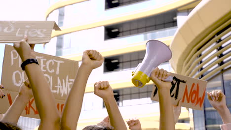 people on a protest raising their hands with boards and a megaphone