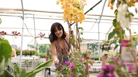 happy young woman exploring nursery touching blooming flowers