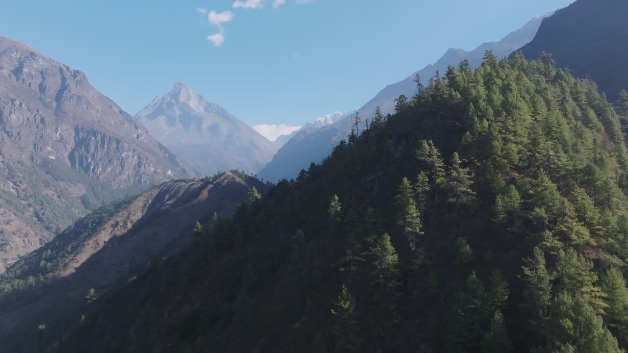 Upward aerial view of Everest region showing lush forested hills, sunlight on horizon, and serene green terrain under clear sky of sagarmatha national park Phakdi Nepal