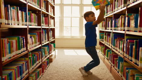 a young boy reaching for and selecting books in a library.