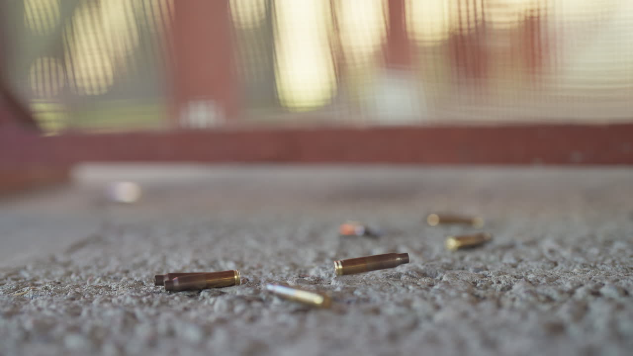 Close up shot of bullets hitting the floor after being shot, static shot