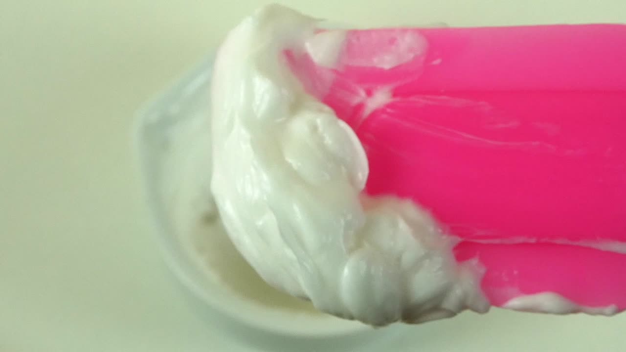 Macro shot of a cosmetic laboratory process where gloved hands in blue gloves mix a cream using a porcelain mortar and pestle.