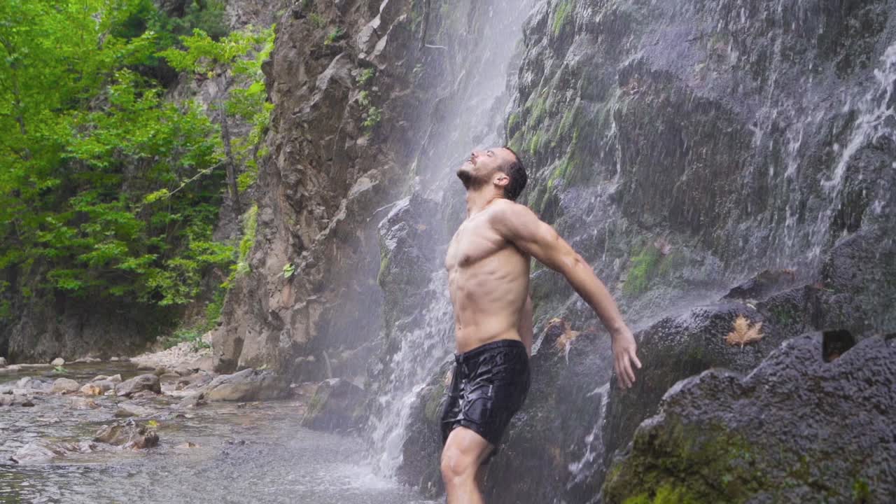 폭포  ⁇ 에 서 있는 강한 남성. 슬로우 모션.