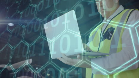 man wearing safety vest using laptop in warehouse, showing hexagon overlay, binary code for tech
