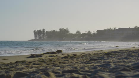 Stationary-shot-of-wave-crashing-into-the-shores-of-Ventura-Beach-on-a-misty-morning-with-Seagull-flying-thorough-the-frame-at-the-end