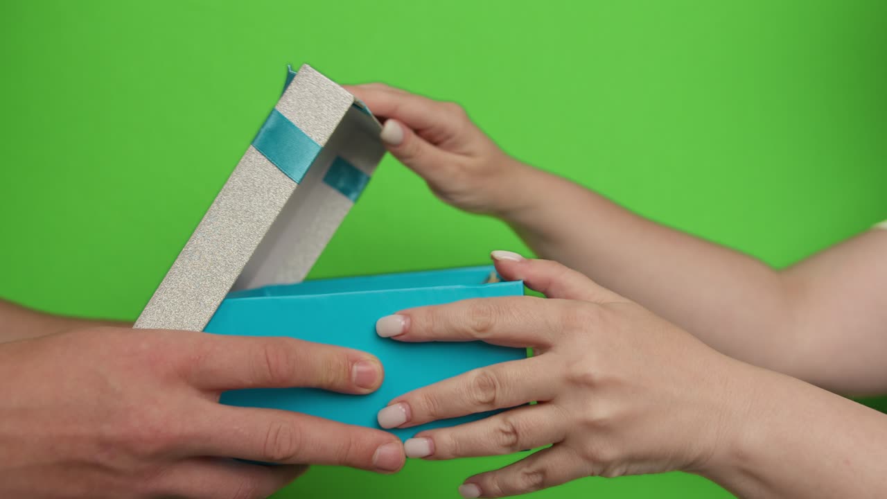 Man giving woman a box with money inside, holidays concept, green background