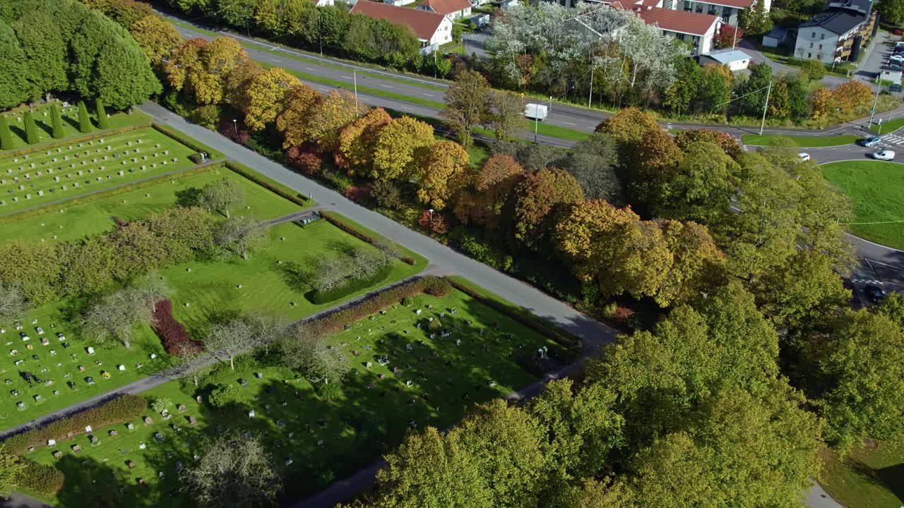 Drone orbit around Kviberg Cemetery with symmetrical grave plots, green lawns, and autumn foliage in Gothenburg, Sweden
