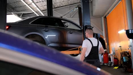 mechanic working in an auto repair shop with a car on a lift