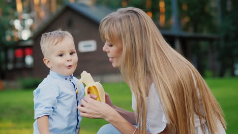 young mother feeding a kid with a banana 4k video