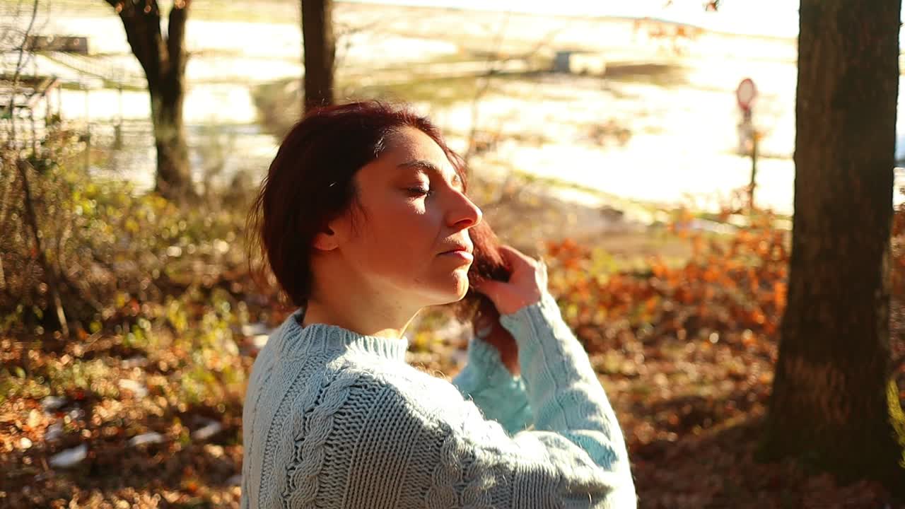 숲 속의 일몰에 빨간 머리를 만지는 젊은 백인 소녀, 느린 동작 중간 샷