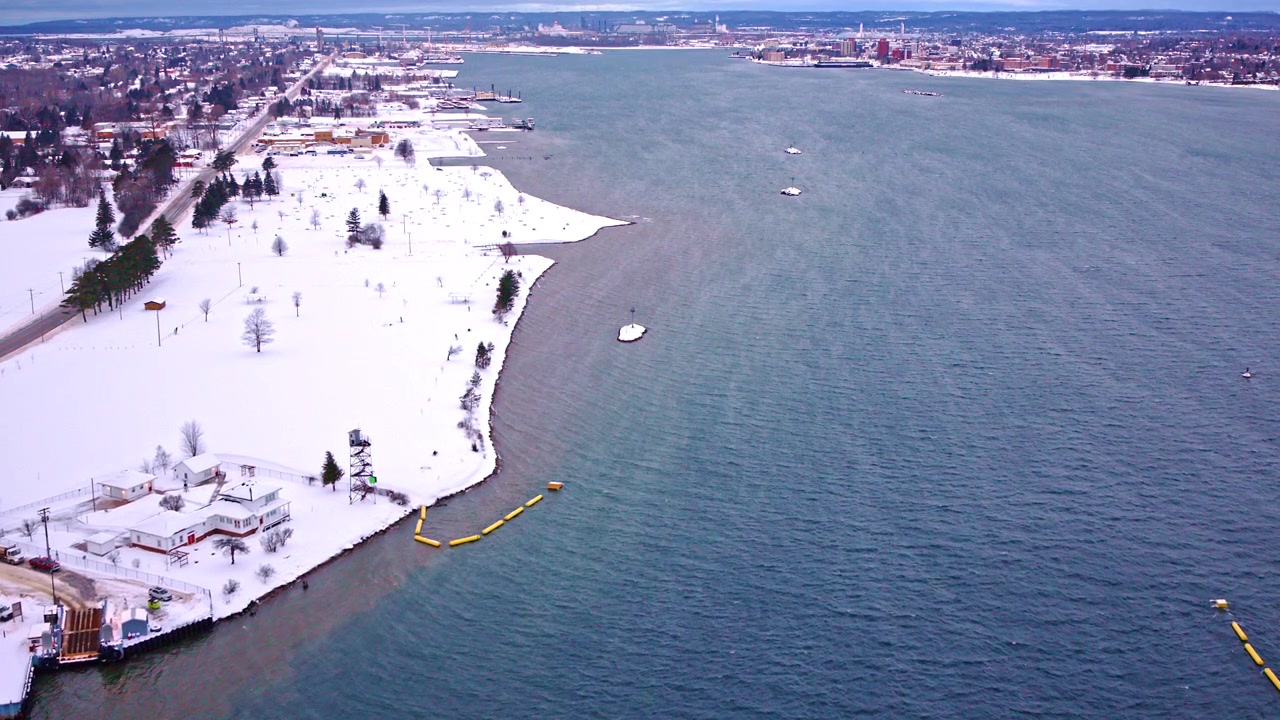 Riprese aeree con drone che sorvolano la costa ghiacciata del Lago Superiore, con scogliere innevate, acqua gelida, litorale aspro, foresta boreale, paesaggio invernale e scenari remoti dei Grandi Laghi.
