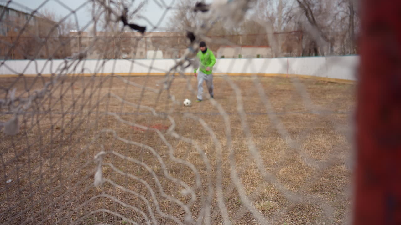 손상된 그물을 통해 선수에게 접근하는 모습, 외로운 개인이 풍화된 그물 배경을 뚫고 목표를 향해 접근합니다. 외톨이 남성이 경기장에서 찢어지고 오래된 그물 구조 뒤의 목표를 향해 나아가고 있습니다.