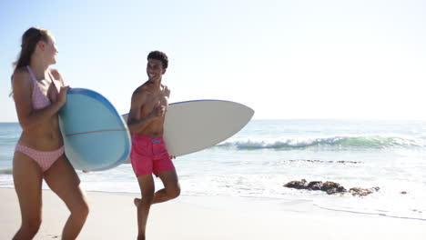una joven mujer caucásica en un bikini rosado con puntos disfruta de un soleado día de playa con su tabla de surf