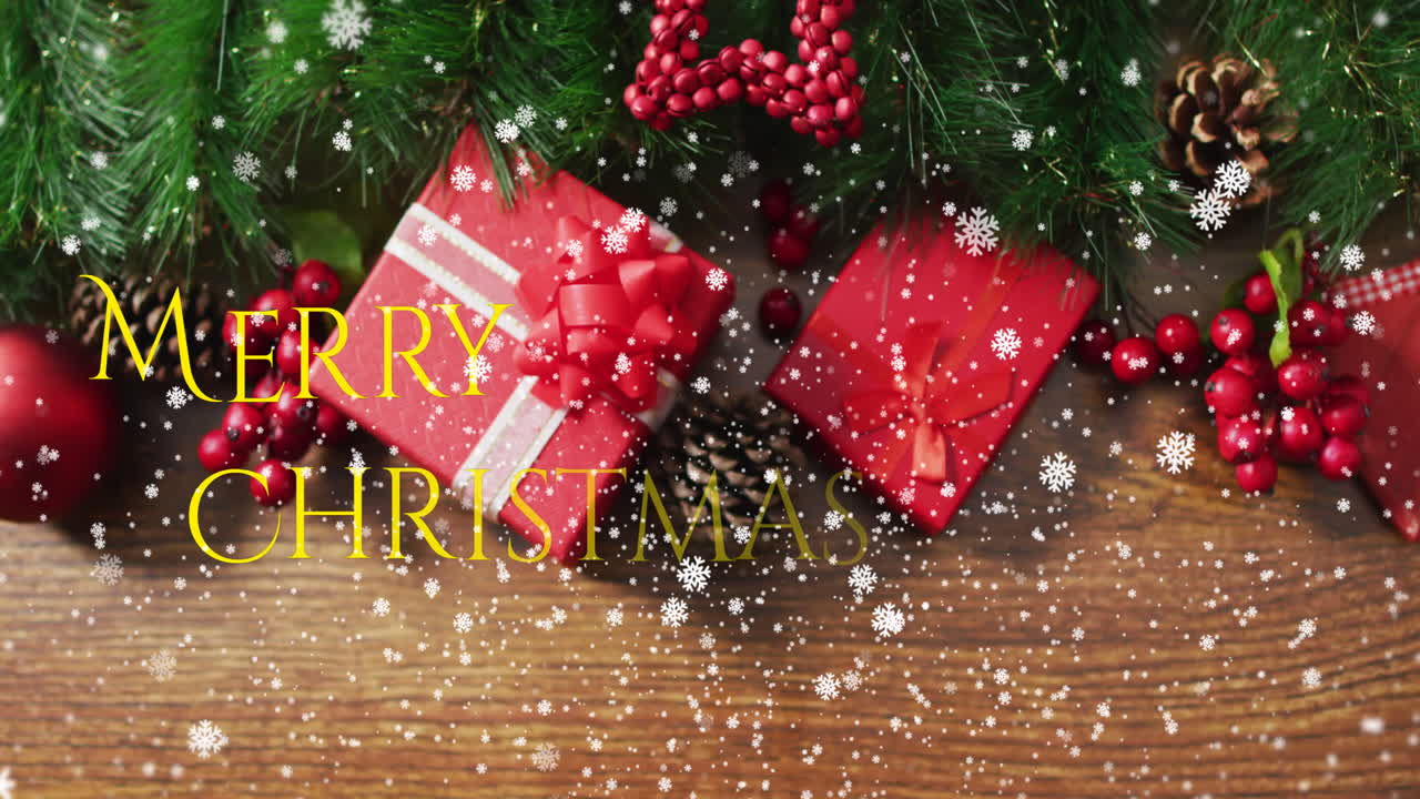 Animation of snow falling over merry christmas text against gifts and decorations on wooden surface