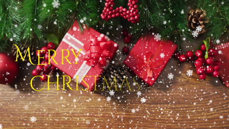 animation of snow falling over merry christmas text against gifts and decorations on wooden surface