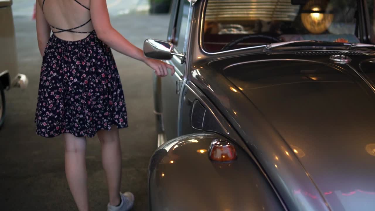 modelo de coche femenino acariciando un hermoso coche de época ampliamente reconocido como el alemán hecho volkswagen escarabajo o punch buggy