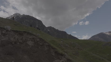 Low-aerial-shot-up-a-hill-show-hikers-at-the-edge-near-the-valley