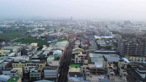 un denso paisaje urbano al anochecer, insinuando la bulliciosa vida en la ciudad, con un cielo brumoso, vista aérea