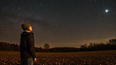 a person gazing at a vast starry night sky in a field