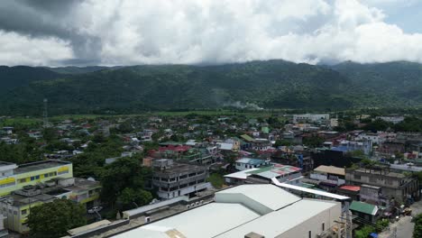 Stunning-aerial-view-of-a-rural-Asian-town-center-in-Catanduanes-with-lush-forests-and-majestic-mountains-in-the-background