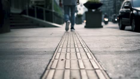 low angle shot of man walking away, busy street, tactile tiles for blind people