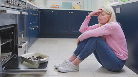 menopausal mature woman with poor memory burning meal in oven at home