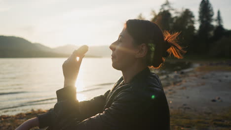 woman eating orange on lake bank at sunset. smiling lady enjoys spending time on picnic with partner. watching beauty of nature at sunset of autumn evening