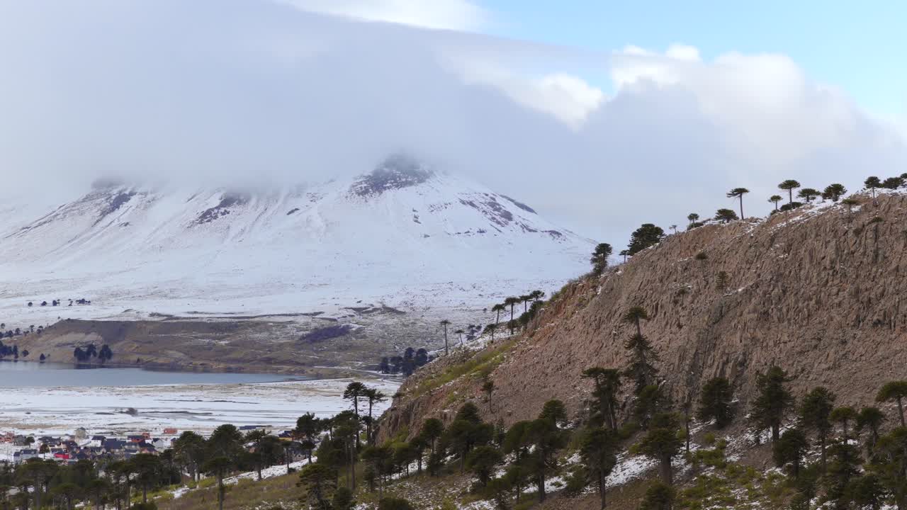 Distant snow capped volcano's environment with barren hillside before in Caviahue-Copahue, Neuquén, Argentina