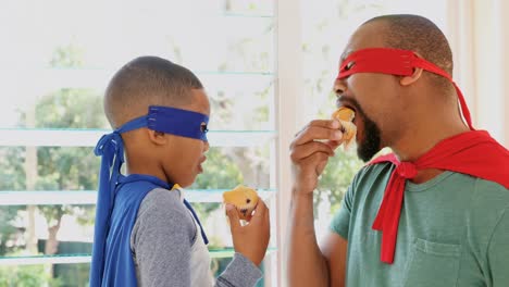 padre e hijo comiendo muffins mientras fingen ser superhéroes 4k